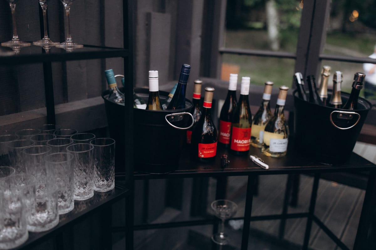 Bartender adds crushed ice to a vibrant red cocktail with a metal scoop at a dimly lit bar